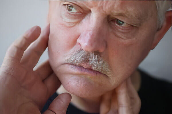 image of man in pain pressing his fingers against his jaw