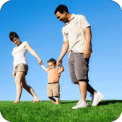 A young boy holding hands with his parents while walking